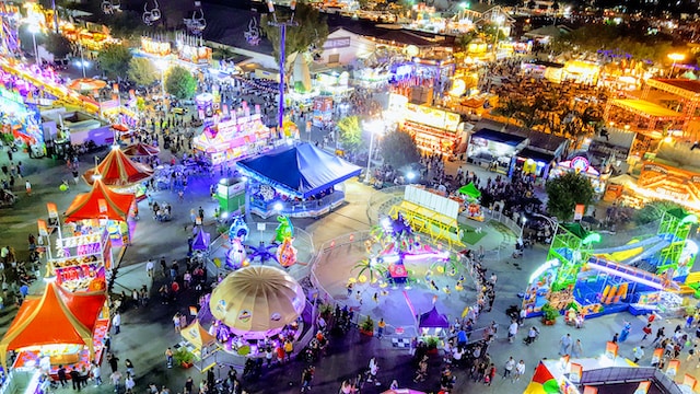 "Captivating aerial view of the lively Boomtown Fair 2022, showcasing vibrant tents, enthusiastic crowds, and immersive stages, creating a kaleidoscope of color and energy."